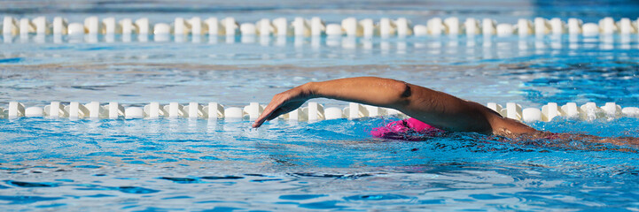 Swimmer woman athlete swimming in pool lanes doing a crawl lap. Swim race freestyle. Triathlete...