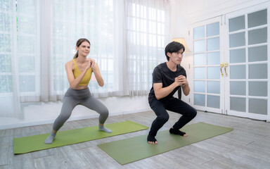 Fototapeta na wymiar Man and woman in sportswear doing yoga exercises together at the gym.