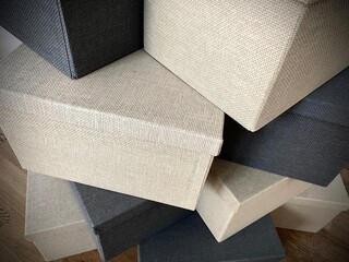 close-up of boxes with blank white labels standing chaotically on top of each other. Lots of stacked storage boxes made of fabric in dark and light colors close-up. Home box storage system close up.