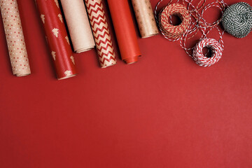 Christmas preparations with paper roll and decorative ropes on red background.