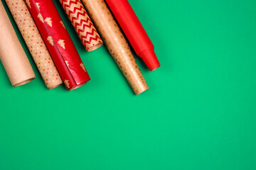 Rolls of red and brown wrapping paper for gifts on green background.