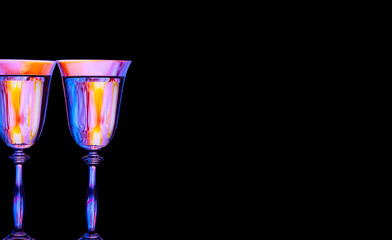 Two sparkling colored wine glasses on a black background. Holiday and party atmosphere.