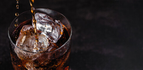 refreshing drink, cold soda with ice cubes in a glass on a black background