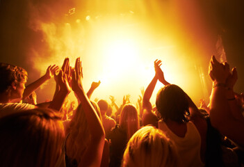 Music, concert and crowd with light, clapping for live performance, rock event and band on stage at night. People, audience and music festival, audio and sound with energy at show with musical artist