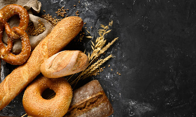 Fresh baked bread assortment on black textured board background. Top view