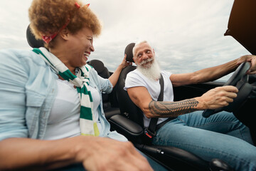 Happy elderly couple having fun driving convertible car during a road trip - Travel people...