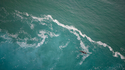 Fototapeta na wymiar Top view of a man paddles a kayak in raging sea water