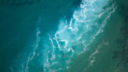 Top view  of a man paddles a kayak in raging sea water - obrazy, fototapety, plakaty