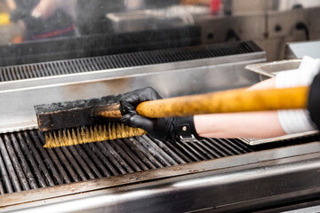 chef hands with metal brush clean the grill oven in kitchen
