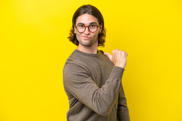 Caucasian handsome man isolated on yellow background proud and self-satisfied