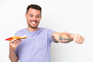 Young caucasian man holding sashimi isolated on white background giving a thumbs up gesture