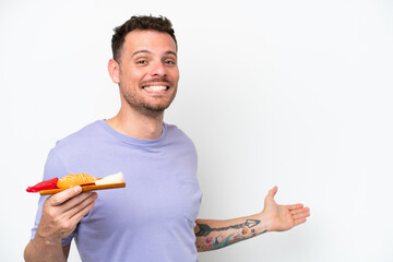 Young caucasian man holding sashimi isolated on white background extending hands to the side for inviting to come