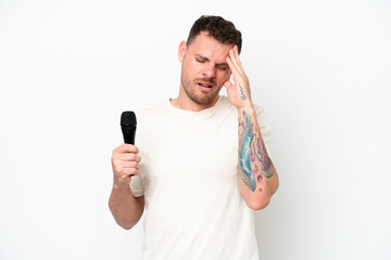 Young caucasian singer man picking up a microphone isolated on white background with headache