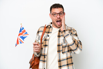 Young hispanic man holding an United Kingdom flag isolated on white background with surprise and shocked facial expression