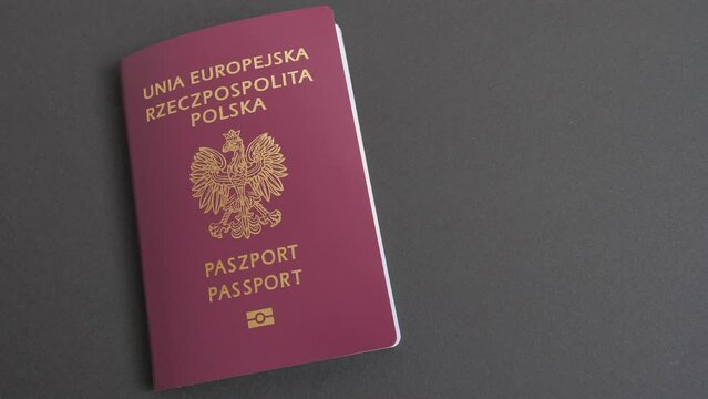 Placing Polish Passport on a table before travel. Black background.