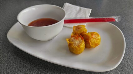 Fried dumpling on the white plate with sweet chili sauce on the bowl, tissue and chopsticks