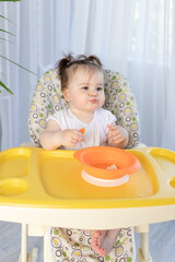 baby girl sitting in a high chair and laughing, baby food concept