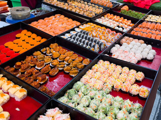 Sushi roll assortment on street market stall display. Variety of Japanese food on stand in Phuket...