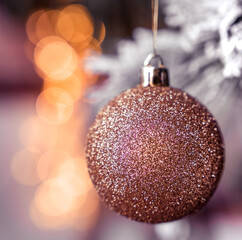 Gold glitter Christmas tree glass ball bauble decoration, golden bokeh, snowy background