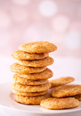 Fototapeta na wymiar Stack of homemade snickerdoodle cookies in a white plate on a pink bokeh effect background with copy space
