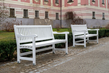 Fototapeta na wymiar Symmetrical two white bench in front house.
