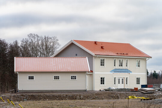 Image of Unfinished scandinavian style wooden house with white siding and orange traditional roof