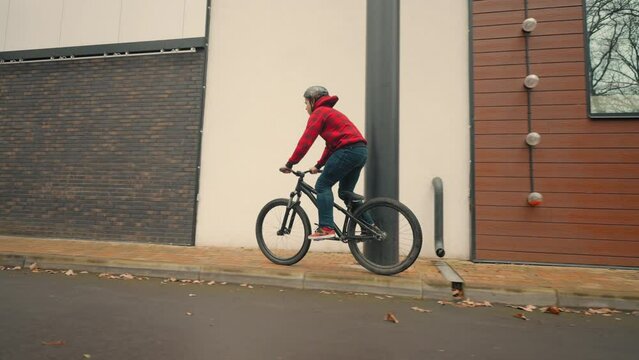 teen boy training bmx tricks modern bicycle on city street, falling on ground after fail bounce