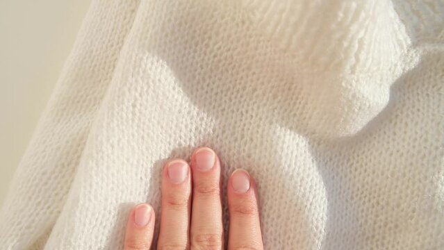 Close up hand stroking over the surface knitted soft wool cloth or warm fluffy sweater. Handcraft knitting woolen fabric.