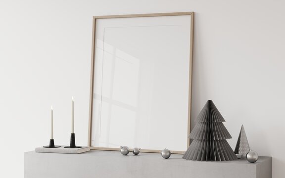 An empty frame on a concrete fireplace with a Christmas stylish decor, a grey paper tree, Christmas toys, candles in a candlestick. Mockup frame for christmas	