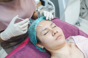 Chemical injections for facial skin care on the forehead of an Asian woman, in a beauty clinic.
