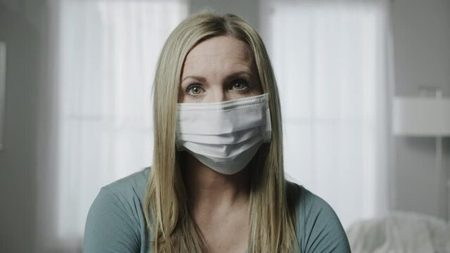 Close up portrait of woman wearing surgical mask looking at camera / Cedar Hills, Utah, United States