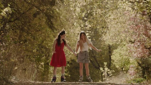 Low angle view of girls teaching friend inline skating on park path in autumn / American Fork Canyon, Utah, United States