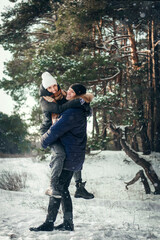 A boy and a girl in love are walking in a pine forest in winter