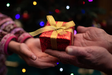 クリスマスプレゼントを手渡す老人と孫娘の手