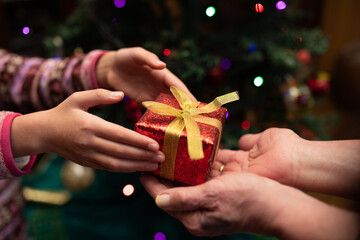 クリスマスプレゼントを手渡す老人と孫娘の手