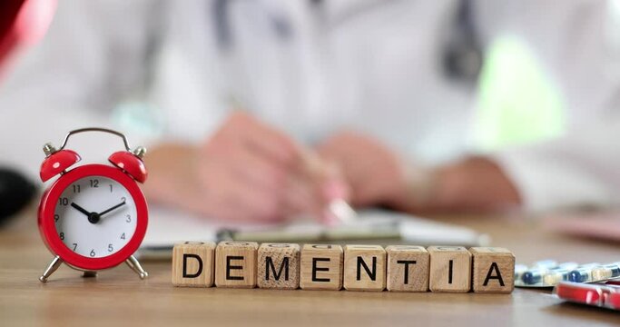 Word dementia from wooden cubes near red alarm clock closeup 4k movie slow motion 