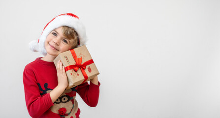 Obraz premium Excited funny dutch caucasian child girl boy wear red Santa hat holding Christmas gift boxes dreaming over white background. Copy space. Merry Christmas presents shopping sale.