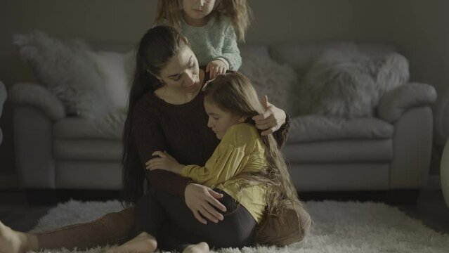 Slow motion of mother sitting on floor comforting daughters / South Jordan, Utah, United States