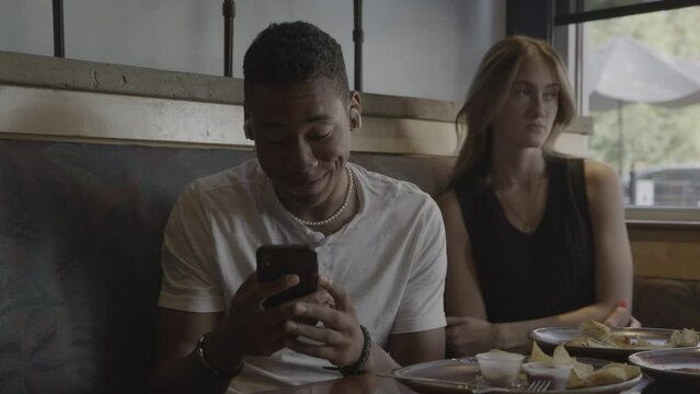 Man in restaurant video chatting on cell phone ignoring woman / Provo, Utah, United States