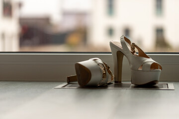 White high heel pumps in front of a window and on a light floor
