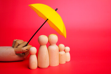 a family of wooden figures protected by a yellow umbrella. Family care, protection and insurance...