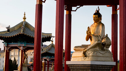 Buddhist statue on a pedestal illuminated by the setting sun
