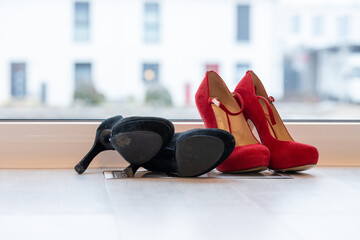 Red and Black high heel pumps in front of a window and on a light floor