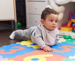 Adorable hispanic baby crawling on floor at kindergarten