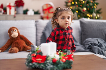 Adorable caucasian girl standing by christmas tree at home