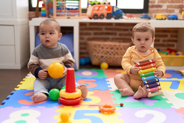 Two toddlers playing with ball and xylophone at kindergarten