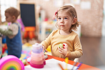 Naklejka premium Adorable hispanic girl playing with hoops game sitting on table at kindergarten