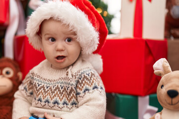 Adorable caucasian baby playing with car toy sitting on floor by christmas gifts at home