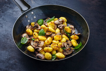Traditional Italian gnocchi di patate with mushrooms as close-up in a frying pan with copy space