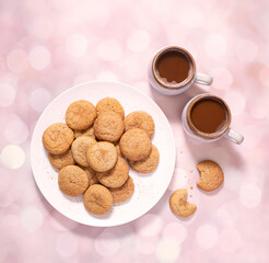 Overhead view of homemade snickerdoodle cookies in a white plate and two cups of coffee with copy space